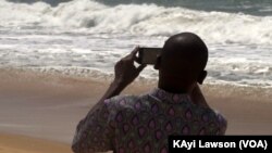 Un curieux photographie les vagues sur la côte du village d'Afidégnigba au Togo, 19 septembre 2018. (VOA/Kayi Lawson)