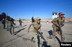 Shiite Popular Mobilization Forces (PMF) members run with their weapons on the outskirts of Hawija, Iraq, Oct. 4, 2017.