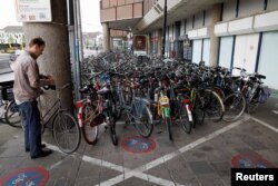 A cyclist parks his bike on the street near the world's largest bike parking garage in Utrecht, Netherlands Aug. 21, 2017.