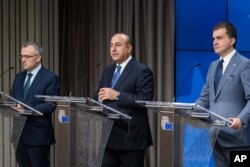 FILE - Turkey's EU Affairs Minister Omer Celik, right, Foreign Minister Mevlut Cavusoglu, center, and Finance Minister Agbal Nihat address the media after an EU Turkey Accession Intergovernmental Conference at the EU Council building in Brussels, June 30, 2016.