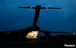 FILE - Crew on an Australian Air Force C-17 Globemaster prepare to unload an Australian Navy Seahawk helicopter.