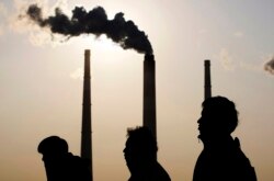 People walk past a power plant in Shanghai on December 5, 2009.