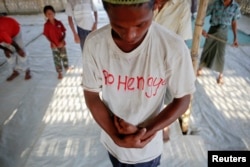 A Rohingya Muslim with the word "Rohingya" written on his T-shirt prays with others at a makeshift mosque at a camp for those displaced by violence, near Sittwe April 28, 2013.