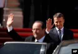 FILE - New French President Emmanuel Macron, right, smiles as outgoing President Francois Hollande waves during Macron's inauguration ceremony as French President, at the Elysee Palace in Paris, May 14, 2017.