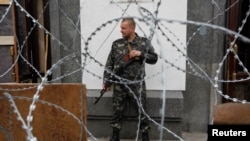 A pro-Russian gunman stands guard outside an administrative building in the eastern Ukrainian city of Luhansk May 12, 2014.
