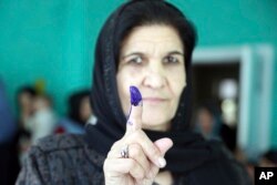 An Afghan woman shows her inked finger after casting her vote at a polling station during the Parliamentary elections in Kabul, Afghanistan, Oct. 20, 2018.