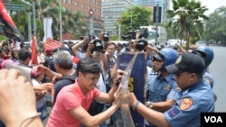 Youth militant leader Vencer Crisostomo pushes against a police shield to get closer to the U.S. embassy in Manila ahead of President Barrack Obama's visit to the Philippines, April 23, 2014. (Simone Orendain/VOA)