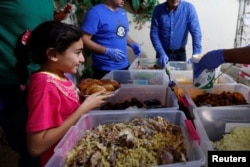 A girl receives a meal provided through the initiative, Family Kitchen, in Al-Baqaa Palestinian refugee camp, near Amman, Jordan, June 11, 2018.