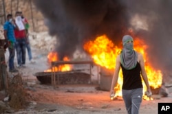 A Palestinian demonstrator holds rocks during clashes with Israeli security forces, at Hizme checkpoint near the West Bank city of Ramallah, Sept. 30, 2015.