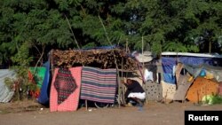 A refugee cleans his tent in a makeshift camp on the Hungary-Serbia border, on the Serbian side of a transit zone set up by Hungarian authorities to filter refugees at Roszke, Hungary, Sept. 2, 2016.