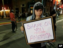 Felomina Cervantes, of Seattle, holds a sign that reads "Shame on You America" as she takes part in a protest against President-elect Donald Trump, Nov. 9, 2016, in Seattle's Capitol Hill neighborhood.