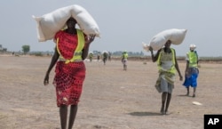 FILE - Women walk back to their homes after receiving food distributed by the International Committee of the Red Cross at a site in the Leer County region of South Sudan, April 11, 2017. Two months after a famine was declared in two counties amid civil war, hunger has become more widespread than expected, aid workers say.