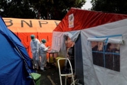 Petugas kesehatan dengan Alat Pelindung Diri (APD) bekerja di antara tenda-tenda darurat yang didirikan di luar ruang gawat darurat untuk menampung kekurangan tempat tidur di rumah sakit milik pemerintah di tengah lonjakan kasus positif COVID-19 di Bekasi, 15 Juli 2021. (REUTERS/Willy Kurniawan/File Photo)