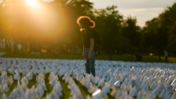 Zoe Nassimoff of Argentina looks at white flags that are part of artist Suzanne Brennan Firstenberg's temporary art installation 'In America: Remember,' in remembrance of Americans who have died of COVID-19, on the National Mall in Washington, Sept. 17, 2