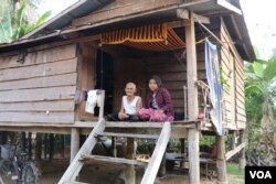 លោកយាយ សៀង ឃឿន និងចៅស្រី អង្គុយខាងមុខផ្ទះតូចមួយ ស្ថិតនៅក្នុងភូមិថ្មី ឃុំសាមគ្គី ស្រុកប្រាសាទបល្ល័ង្ក ខេត្តកំពង់ធំ កាលពីថ្ងៃទី៧ ខែមករា ឆ្នាំ២០១៨។ លោកយាយមានប្រសាសន៍ថា ពេលខ្លះ ចៅមកគេងមើលថែលោកយាយនៅពេលយប់។ (ស៊ុន ណារិន/VOA)