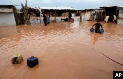 Pakistani villagers collect their belongings following flash flooding on the outskirts of Peshawar, Pakistan, Sunday, April 3, 2016.