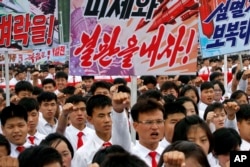 Tens of thousands of men and women pump their fists and chant as they carry placards with anti-American propaganda slogans at Pyongyang's central Kim Il Sung Square, June 25, 2017, to mark what North Korea calls "the day of struggle against U.S. imperialism," the anniversary of the start of the Korean War.