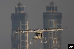 FILE - A Volocopter prototype flies in front of the two hotel towers during a test flight of pilotless taxis in Dubai, United Arab Emirates, Sept. 26, 2017.