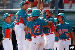 Maracaibo, Venezuela's Jonney Rosario (15) celebrates with teammates after hitting a two-run home run during the first inning of an International pool play baseball game against White Rock, British Columbia.