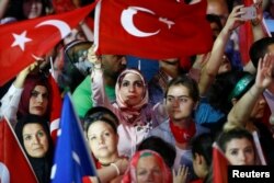People wave Turkey's national flags as they attend a ceremony marking the first anniversary of the attempted coup in front of the Turkish Parliament in Ankara, July 16, 2017.