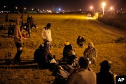 FILE - Migrants wait next to the Eurotunnel area as they attempt to access the Channel Tunnel, in Calais, northern France, July 29, 2015.