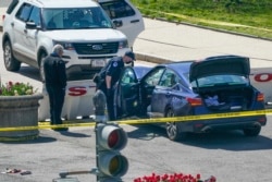 Petugas dari Kepolisian Capitol AS berdiri di dekat sebuah mobil yang menabrak pembatas di depan Gedung Capitol, Washington, D.C., Jumat, 2 April 2021. (Foto AP / J. Scott Applewhite)