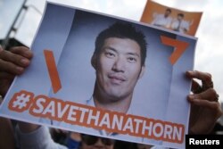FILE - A supporter of Thanathorn Juangroongruangkit, leader of the Future Forward Party, holds up a placard as she reacts during his arrival at a police station in Bangkok, Thailand, April 6, 2019.