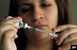 FILE - A woman fills a syringe as she prepares to give herself an injection of insulin.