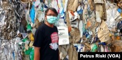 Andreas dari Ecoton dengan latar belakang tumpukan sampah kertas dari Inggris, 28 Juni 2019. (Foto: Petrus Riski/VOA)