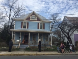 Jodi Beder plays the cello from her front porch as neighbors gather to enjoy the music, in Mount Rainier, Maryland, March 20, 2020 (Ashley Thompson)