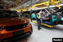 FILE - Worker George Baker looks at a build card for a vehicle destined for China at the Jaguar Land Rover facility in Solihull, England, Jan. 30, 2017.