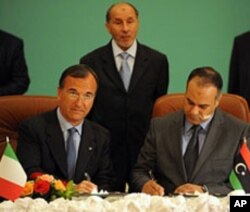 Italian Foreign Minister Franco Frattini (L) signs a memorandum of understanding with Ali al-Essawi (R), the foreign affairs chief in the rebels' National Transitional Council, in the eastern Libyan city of Benghazi, May 31, 2011
