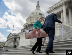 Senate Minority Leader Sen. Chuck Schumer of N.Y., right, and Sen. Elizabeth Warren, D-Mass., carry photographs of their constituents who would be adversely affected by the proposed Republican Senate health care bill after speaking to reporters outside the Capitol in Washington, June 27, 2017.