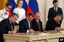 Russian President Vladimir Putin (2nd R) looks on as the Speaker of Crimean legislature Vladimir Konstantinov (2nd L), Crimean Premier Sergei Aksyonov (L), and Sevastopol mayor Alexei Chalyi, (R), sign a treaty for Crimea to join Russia, Moscow, March 18, 2014.