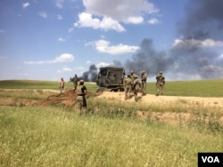 After taking back this field from IS, trucks plow down IS barriers to allow humvees to move into the fight, in Mosul, Iraq, May 4, 2017. (H. Murdock/VOA)