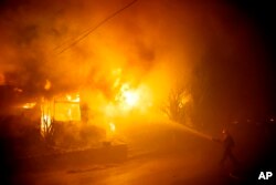 Petugas berusaha memadamkan kebakaran dekat Getty museum di kota Los Angeles, California, hari Senin (28/10).
