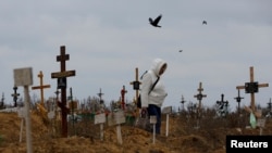 Seorang perempuan mendatangi kuburan di Staryi Krym, di luar Kota Mariupol, pada 9 November 2022, di tengah perang Rusia dan Ukraina yang terus berlangsung. (Foto: Reuters/ Alexander Ermochenko)