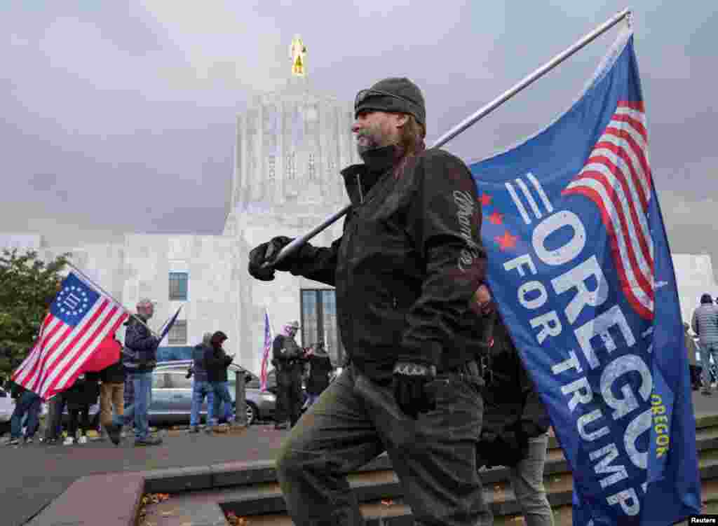 A man carry a flag during a protest after media announced that Democratic U.S. presidential nominee Joe Biden has won the 2020 U.S. presidential election, in Salem, Oregon, Nov. 7, 2020.