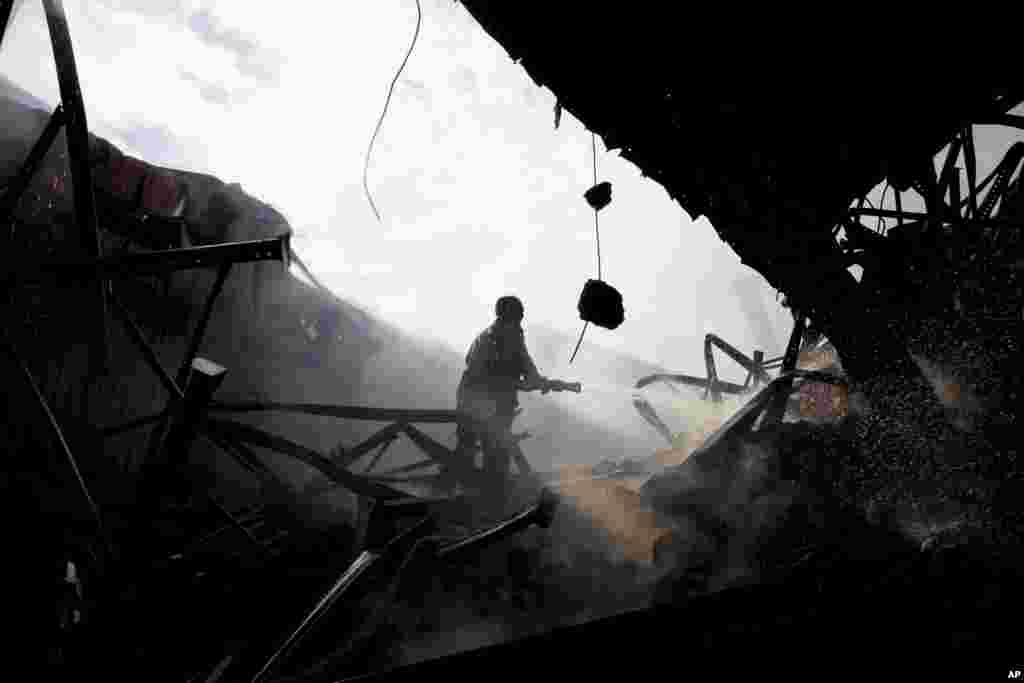 A firefighter tries to douse a fire at a garment factory in Gazipur outside Dhaka, Oct. 9, 2013. 