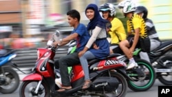 An Acehnese woman straddles on a motorbike on a road in Lhokseumawe, Aceh province, Indonesia, January 7, 2013.