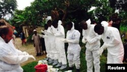 Des travailleurs bénévoles en uniforme de protection contre la maladie à virus Ebola, se préparent à enterrer une vicitme de l'épidémie qui a déjà fait 9.00 morts en Afrique de l'Ouest