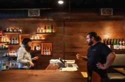 James Mark, right, owner of the Big King restaurant, talks with Jennifer Wittlin as they prepare for takeout orders, March 25, 2020, in Providence, R.I.