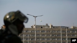 An Indian paramilitary soldier stands guard as the Indian national flag flies atop the government secretariat in Srinagar, Indian controlled Kashmir, Oct. 31, 2019. 
