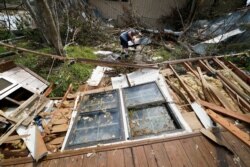 FILE - Bradley Beard digs as he searches in vain for his water shutoff valve, next to his heavily damaged home and the destroyed trailer home of his daughter in Hackberry, La., in the aftermath of Hurricane Laura, Aug. 29, 2020.