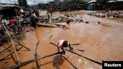 Seorang gadis melangkah melalui banjir udara setelah Sungai Nairobi meluap dan menghancurkan rumah mereka di pemukiman lembah Mathare di Nairobi, Kenya, 24 April 2024. (Foto: REUTERS/Monicah Mwangi)