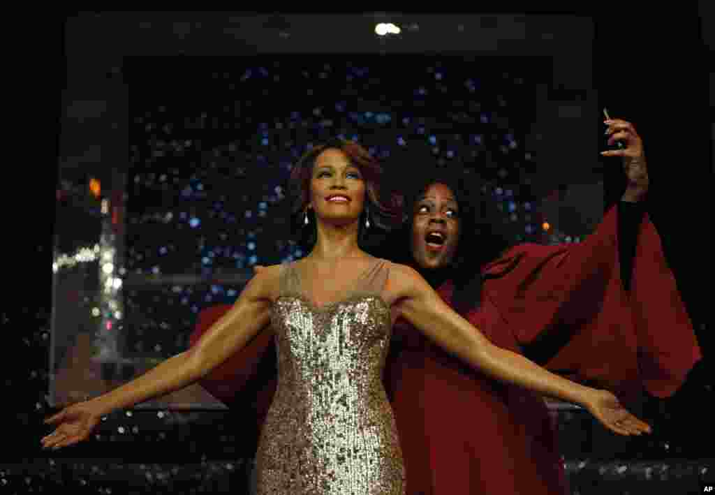 Seorang anggota paduan suara berpura-pura mengambil foto dirinya dengan patung lilin mendiang penyanyi AS Whitney Houston, di museum Madame Tussauds di London. 