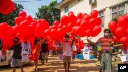 Anti-coup protesters hold red balloons carrying leaflets with various messages before releasing them during a gathering, in Yangon, Myanmar, March 24, 2021.