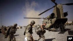 US Army soldiers duck their heads to avoid the exhaust of a helicopter departing Combat Outpost Terra Nova in Kandahar, Afghanistan, 19 Jul 2010.
