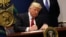FILE - President Donald Trump signs an executive order to impose tighter vetting of travelers entering the United States, at the Pentagon in Washington, Jan. 27, 2017. 