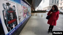 Seorang perempuan China mengamati poster film "Django Unchained" di luar bioskop di Beijing (11/4). 